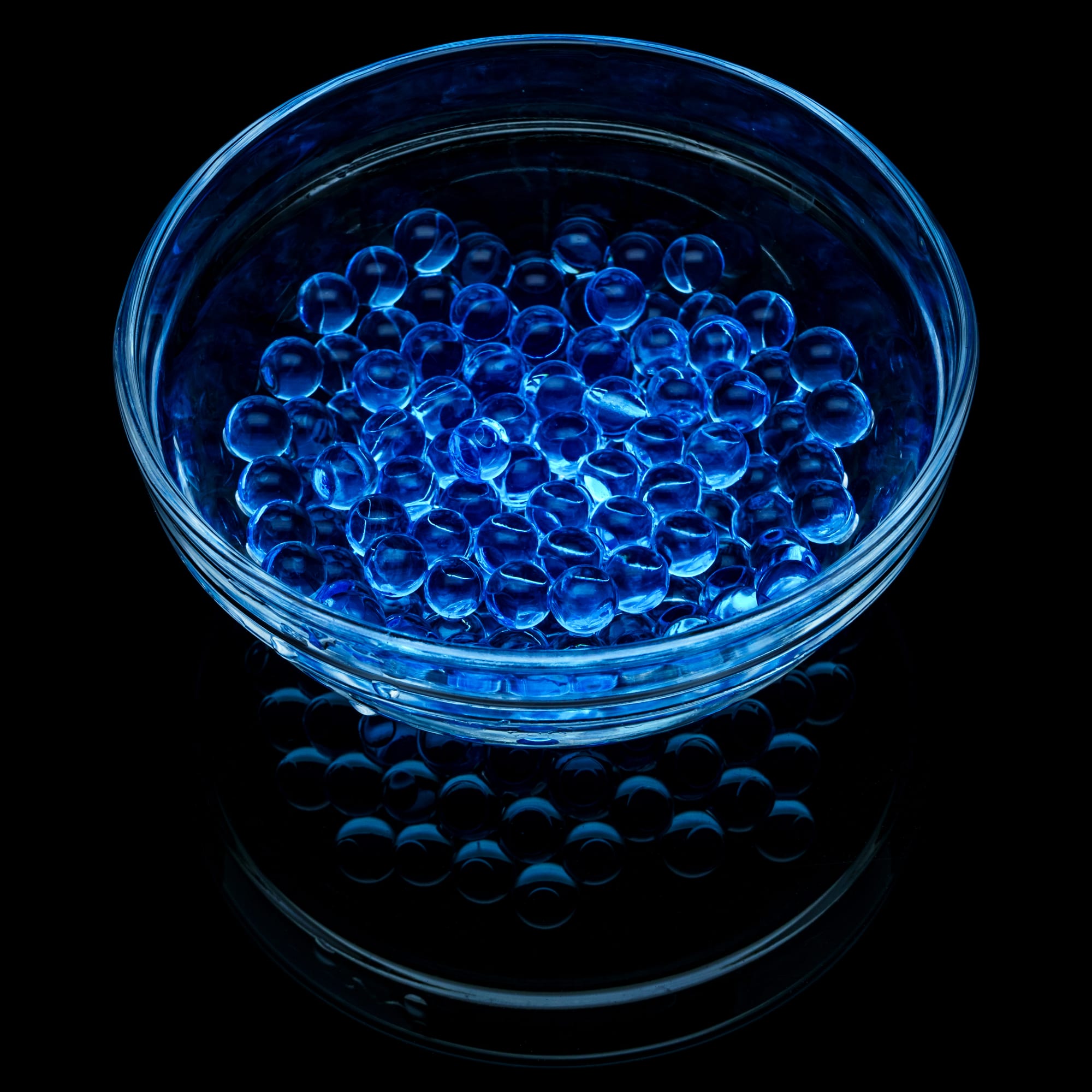 Blue hydrogel balls in a glass vase on a black background