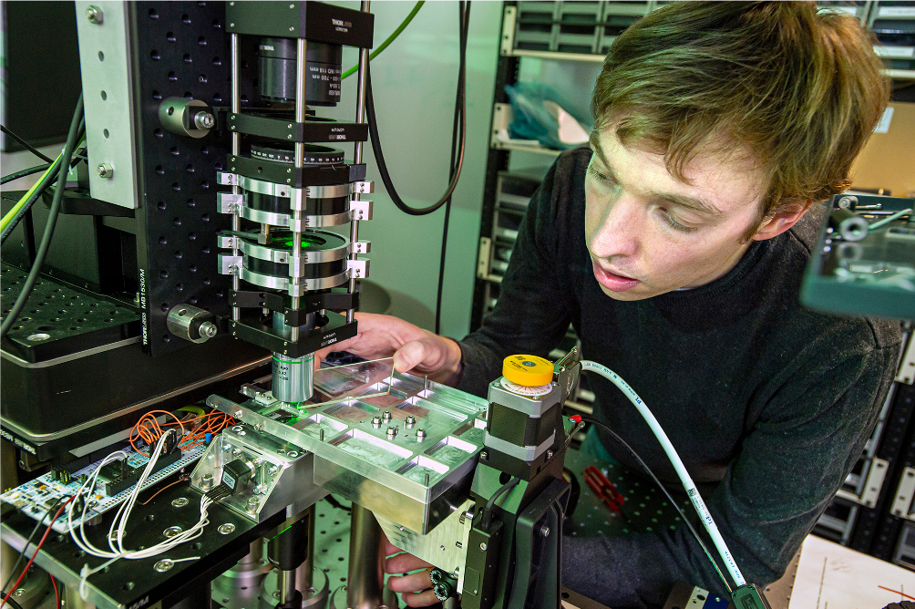Microsoft senior optical scientist James Clegg loads a piece of glass into a system that uses optics and artificial intelligence to retrieve and read data stored on glass. Photo by Jonathan Banks for Microsoft.