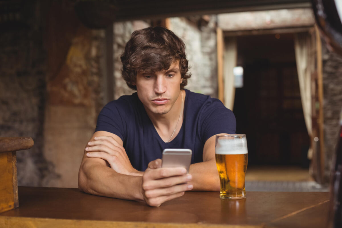 Sei ubriaco? Il tuo smartphone può proteggerti dal rischio di guida in stato di ebbrezza - Man using mobile phone with beer glass on table in bar