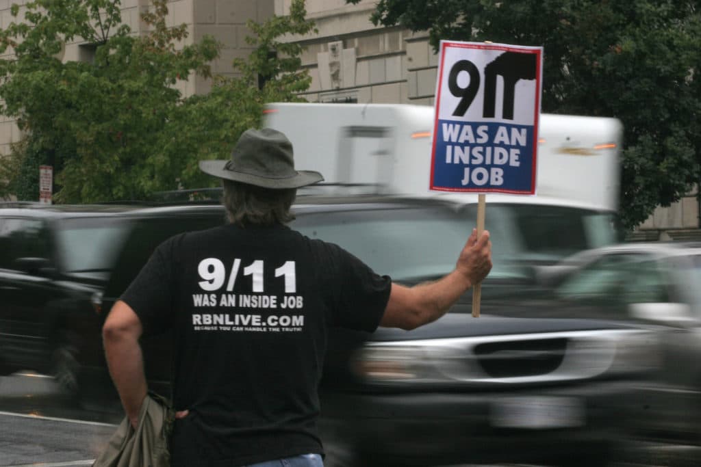 Un manifestante complottista che attribuisce la colpa per l'attentato dell'11 Settembre 2001 agli States stessi. Molte fazioni complottiste sostengono infatti che il tutto sia opera dello stesso governo. Photo by: AFP PHOTO/Nicholas KAMM (Photo credit sho