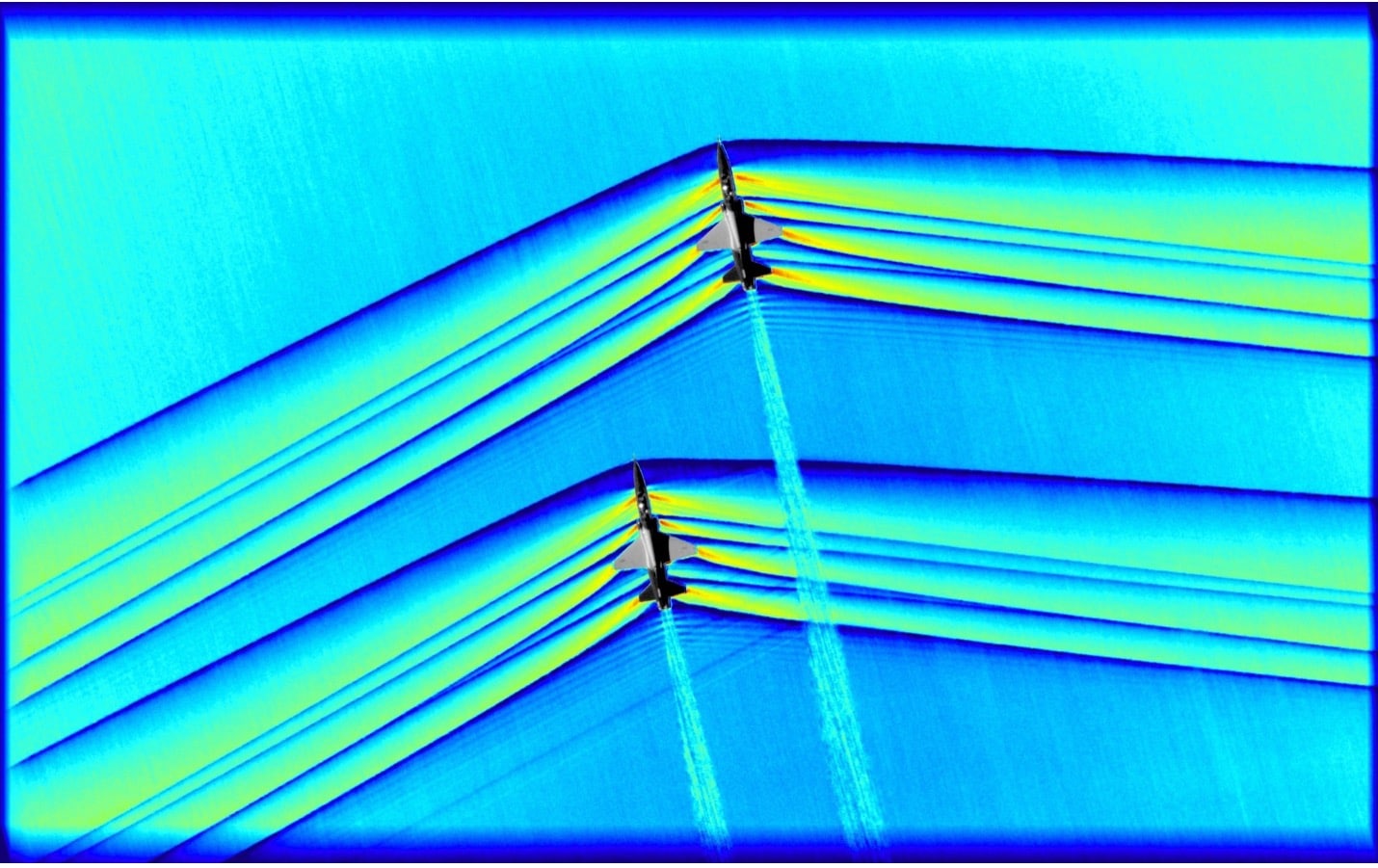 Visualizzazione di onde d’urto generate da due velivoli tramite tecnica Schlieren. Le zone blu sono quelle a densità maggiore: come si può notare, si trovano davanti al velivolo, dal momento che, come detto precedentemente, le molecole si ammassano per po