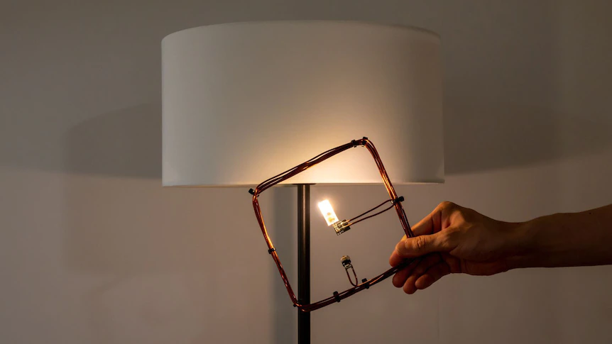 Lampada a LED alimentata dalla bobina di ricezione grazie al campo magnetico generato all'interno della stanza.  Credits: "Michigan News" e The University of Tokyo.