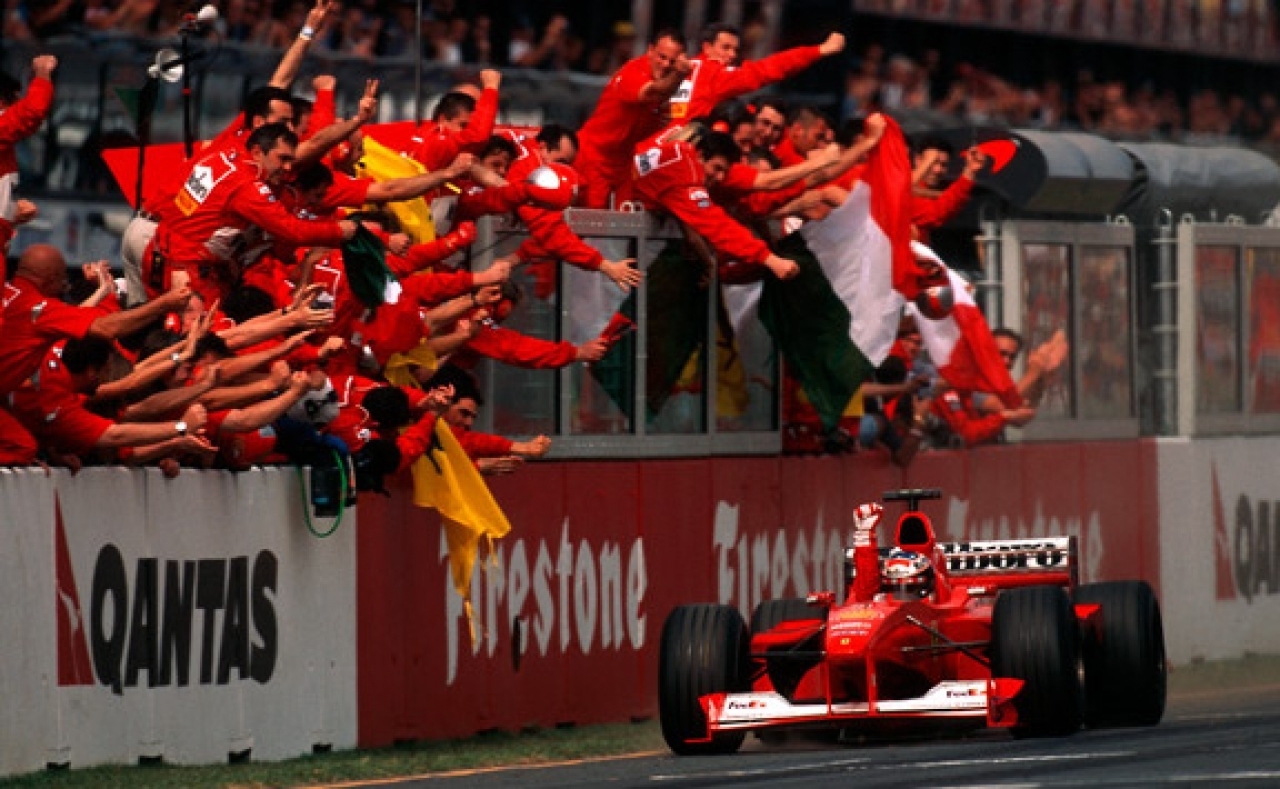 Michael Schumacher taglia il traguardo del GP del Giappone 2000 in prima posizione, con gli uomini in rosso in festaPh: Libera TV