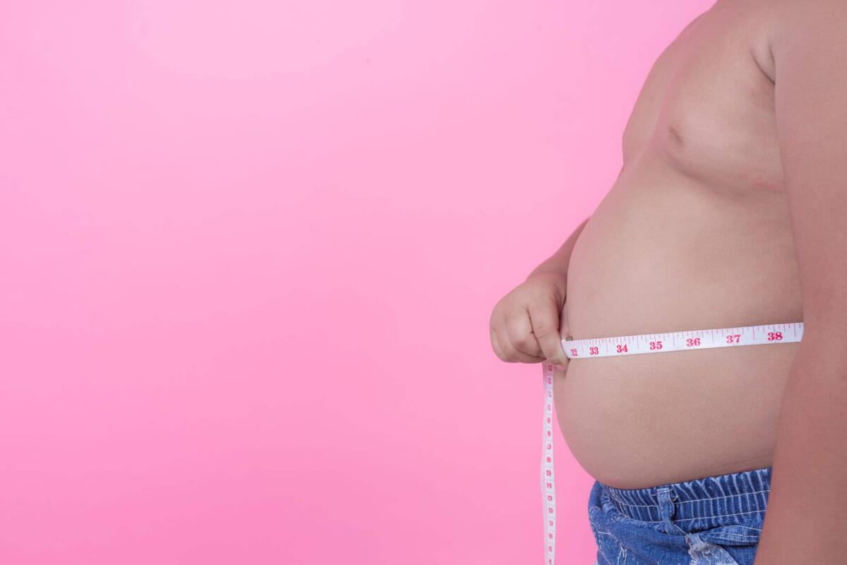 Obesità infantile: maggiore probabilità di avere problemi cognitivi - Obese boy who is overweight on a pink background.