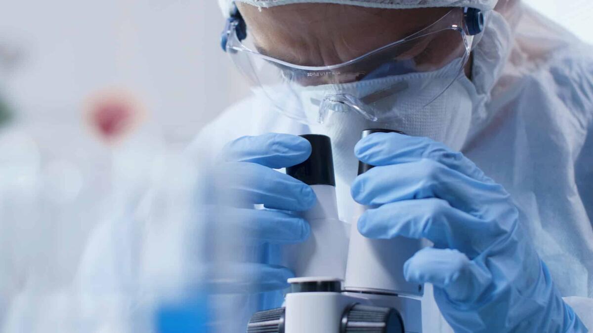 Mappa genetica dei tumori: è pronta e ci dice come crescono - Closeup of scientist doctor looking into medical microscope analyzing blood sample during scientific experiment in biochemistry laboratory. Researcher man developing vaccine against covid19