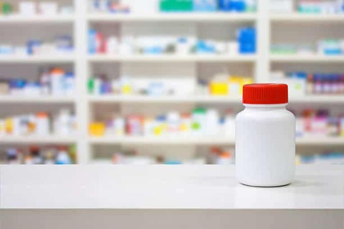 Farmaci da banco: cosa sono? - Blank white medicine bottle on counter with blur shelves of drug in the pharmacy drugstore background