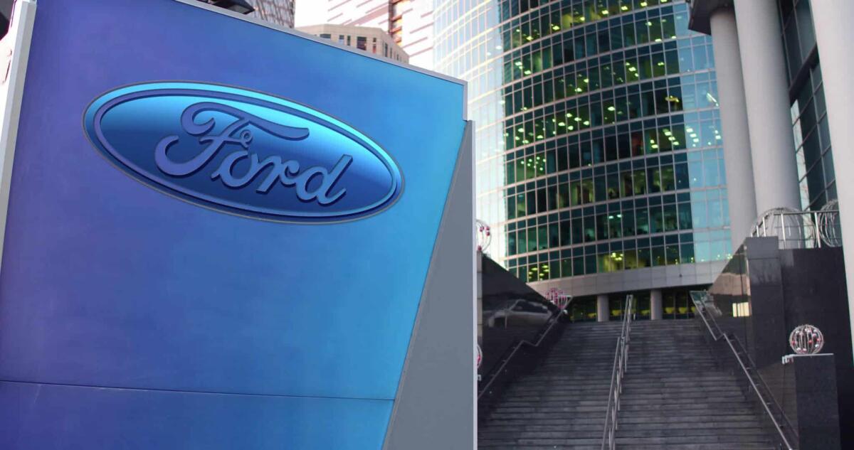 Ford e il "conto salato" presentatogli dall'ingegnere Steinmetz - Street signage board with Ford Motor Company logo. Modern office center skyscraper and stairs background. Editorial 3D rendering United States
