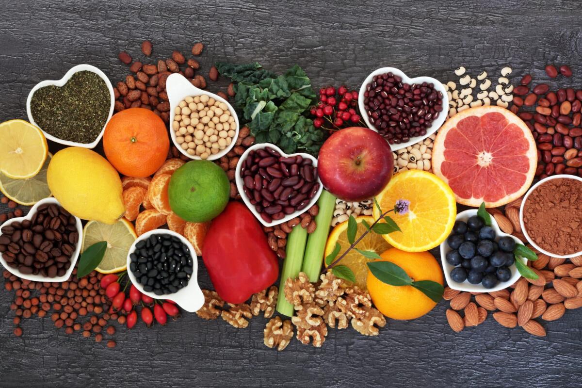 Polifenoli: cosa sono, utilità, dove si trovano, pericolo - Healthy heart food high in flavonoids, polyphenols, antioxidants, anthocyanins, lycopene, vitamins, proteins, bioflavonoids, minerals, fibre. On rustic wood background.