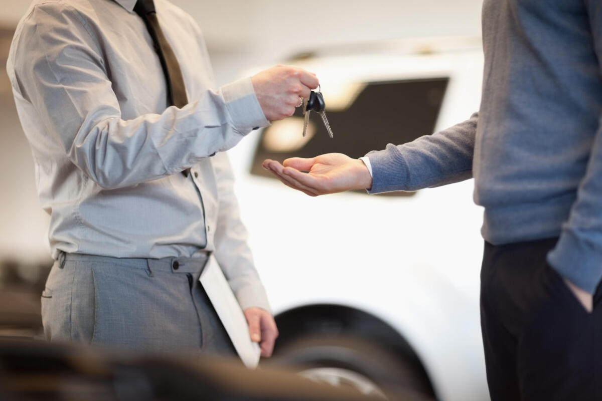 Noleggio auto a lungo termine: come funziona e quanto conviene - Man giving keys to another man in a car shop