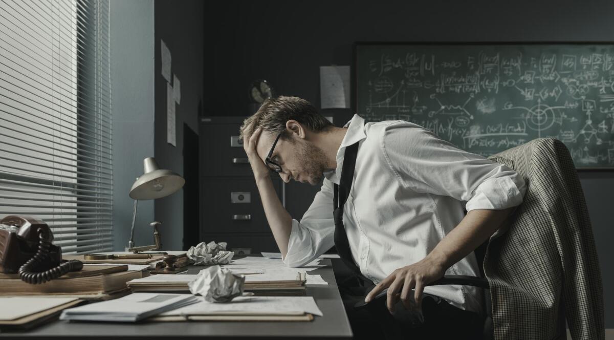 Ecco come battere un matematico al suo stesso gioco - Brilliant young mathematician sitting at office desk and reviewing his papers, he is focused and studying new formulas