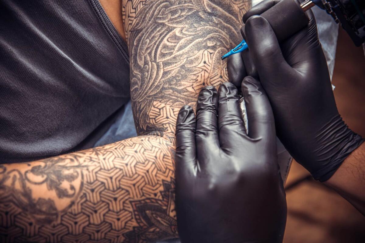 Perché i tatuaggi sono indelebili nonostante i macrofagi? - Tattooist posing in tatoo salon.
