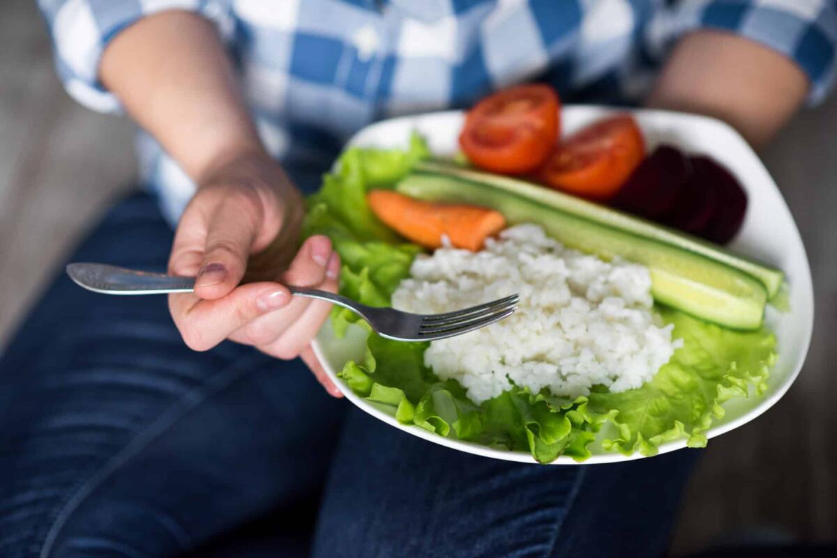 Diete Veg in pediatria: tipologie, stato nutrizionale e rischi - Girl with a plate of vegetables in hands. Healthy eating concept. A girl in jeans and a plaid shirt. Casual Style. Proper nutrition. Diet. Health. Vegetarian food. Vegans food. Small depth of field.