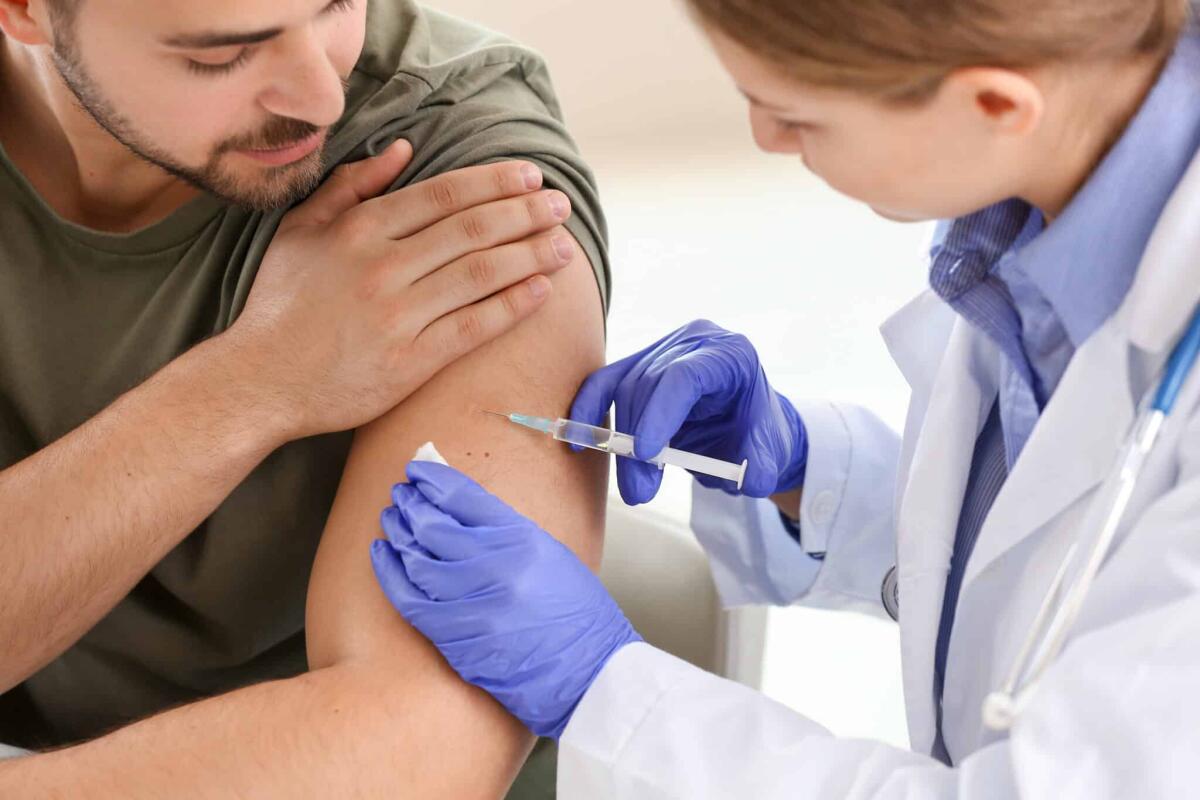 Cancro: da Moderna il nuovo vaccino a mRNA - Doctor vaccinating young man in clinic