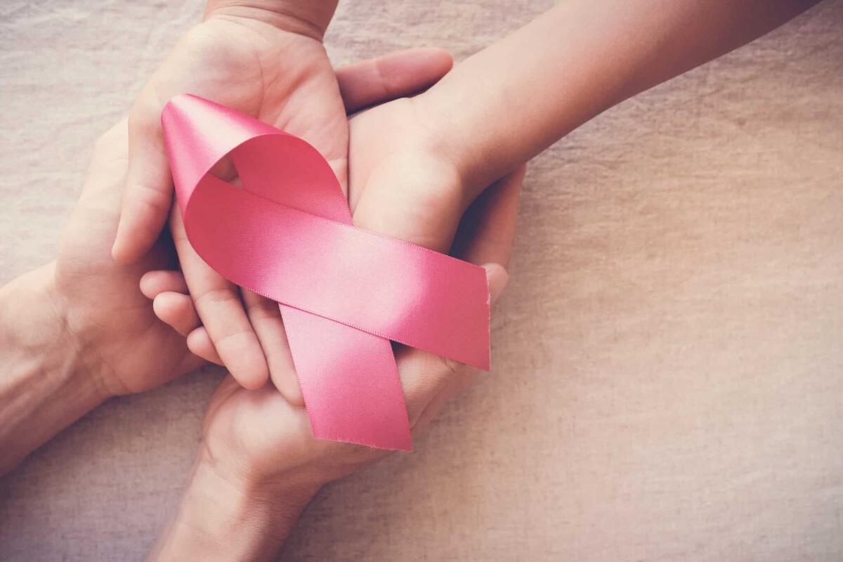 Tumore al seno: l'intelligenza artificiale rivela la terapia - hands holding pink ribbon, breast cancer awareness, October pink concept