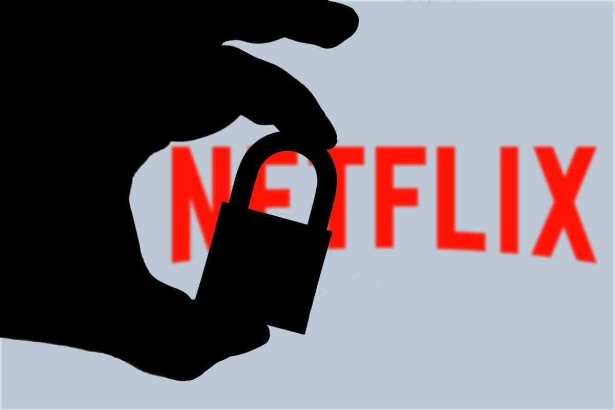 Dietrofront Netflix: rimosso blocco  password condivise - In this photo illustration a man holds a padlock and in the background the logo of Netflix on the computer screen. Online data protection - breach concept. Internet privacy issues