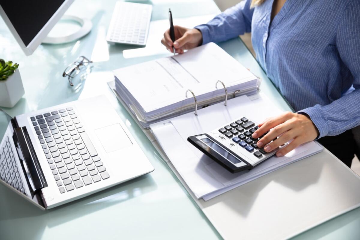 Definizione agevolata: cos'è, come funziona e come accedere - Businesswoman's Hand Calculating Bill With Calculator Over Desk In Office