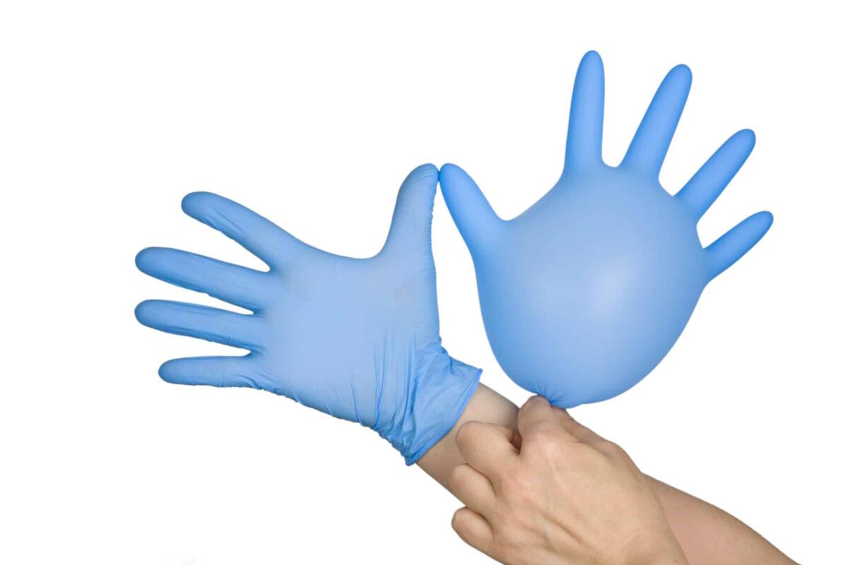 Linfedema: cos'è, come si manifesta e come si cura - Lymphedema: Symptoms, treatments, and causes concept - Hand putting on blue glove, isolated on white background