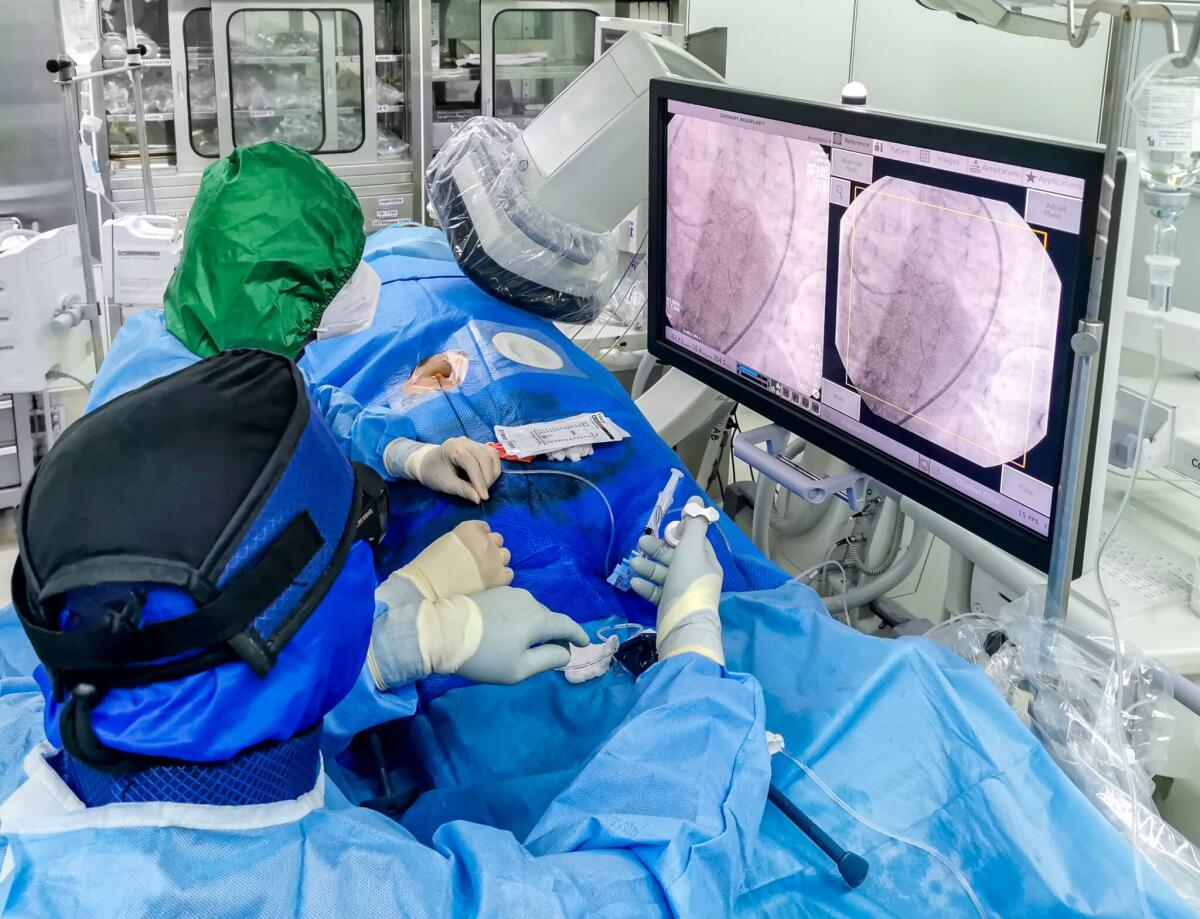 CT-Navigation: nuova frontiera nella radiologia interventistica - This shot shows an ongoing emergency coronary angioplasty procedure perform in a cardiac catheterization laboratory during COVID. The medical staff is in full PPE.