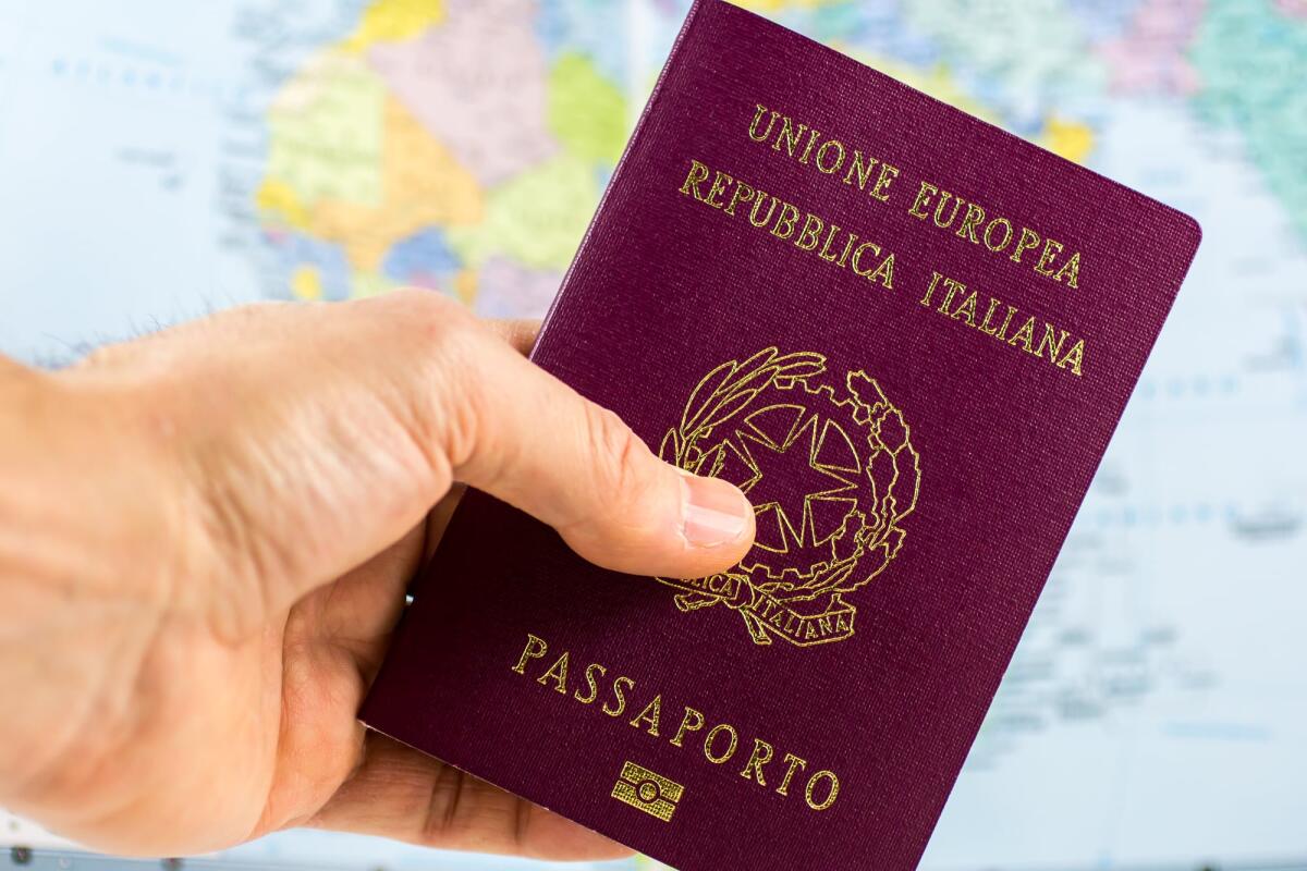 Ritardi nel rilascio dei passaporti: le cause e le conseguenze - hand holds an Italian passport with a blurred map in the background