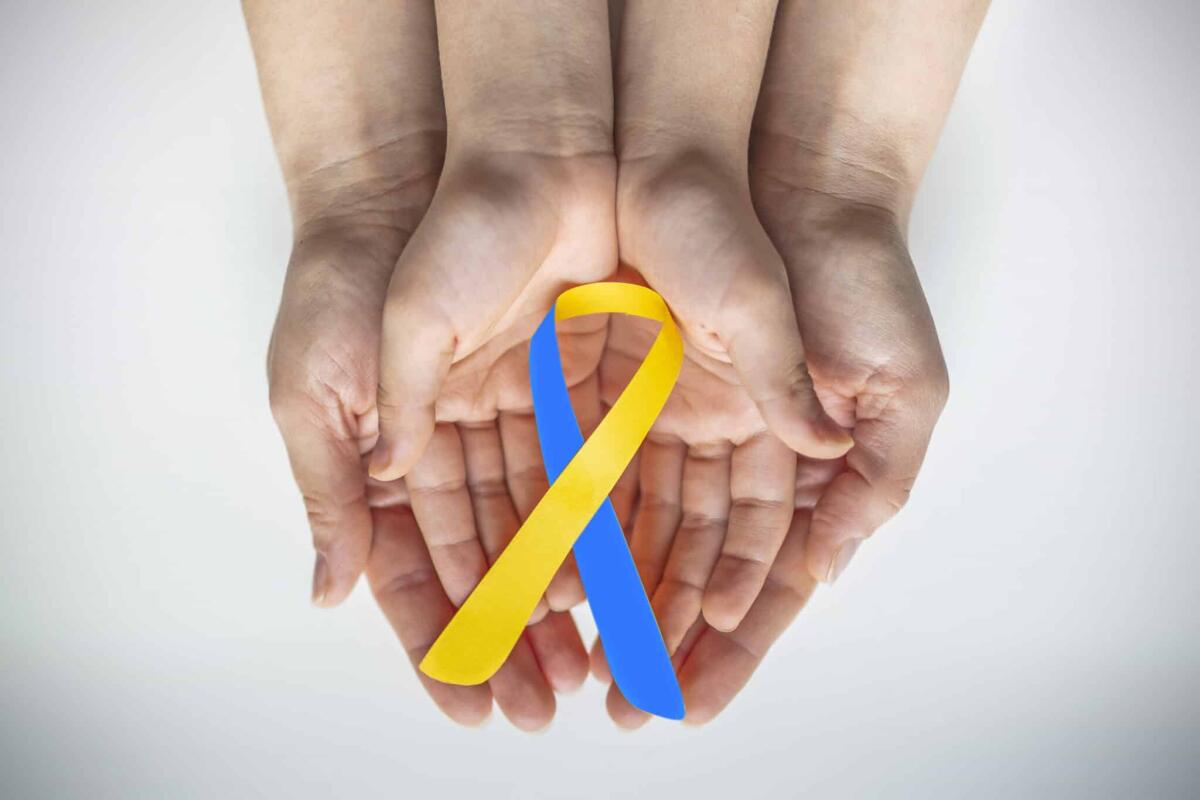 Trisomia 21 o sindrome di Down: cos'è, la diagnosi e la cura - Adult and child hands holding blue and yellow ribbon shaped paper, Down syndrome awareness , World down syndrome day
