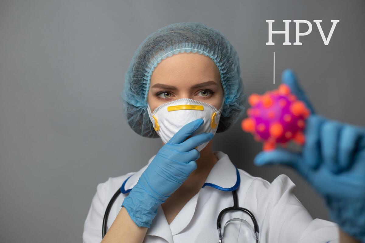 Vaccino Hpv: la copertura del 95% è sempre più lontana - Human papilloma virus concept. Doctor in protective medical clothes on gray background. Holds Abstract strain model. Close up photo.