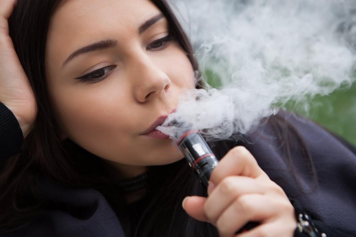 E-cig: le sigarette elettroniche fanno male? - Quit smoking nicotine,start vaping e-juice,e-liquid.Pretty young woman using vaporizer device,modern gadget for smokers.Safe and tasty glycerin vapor