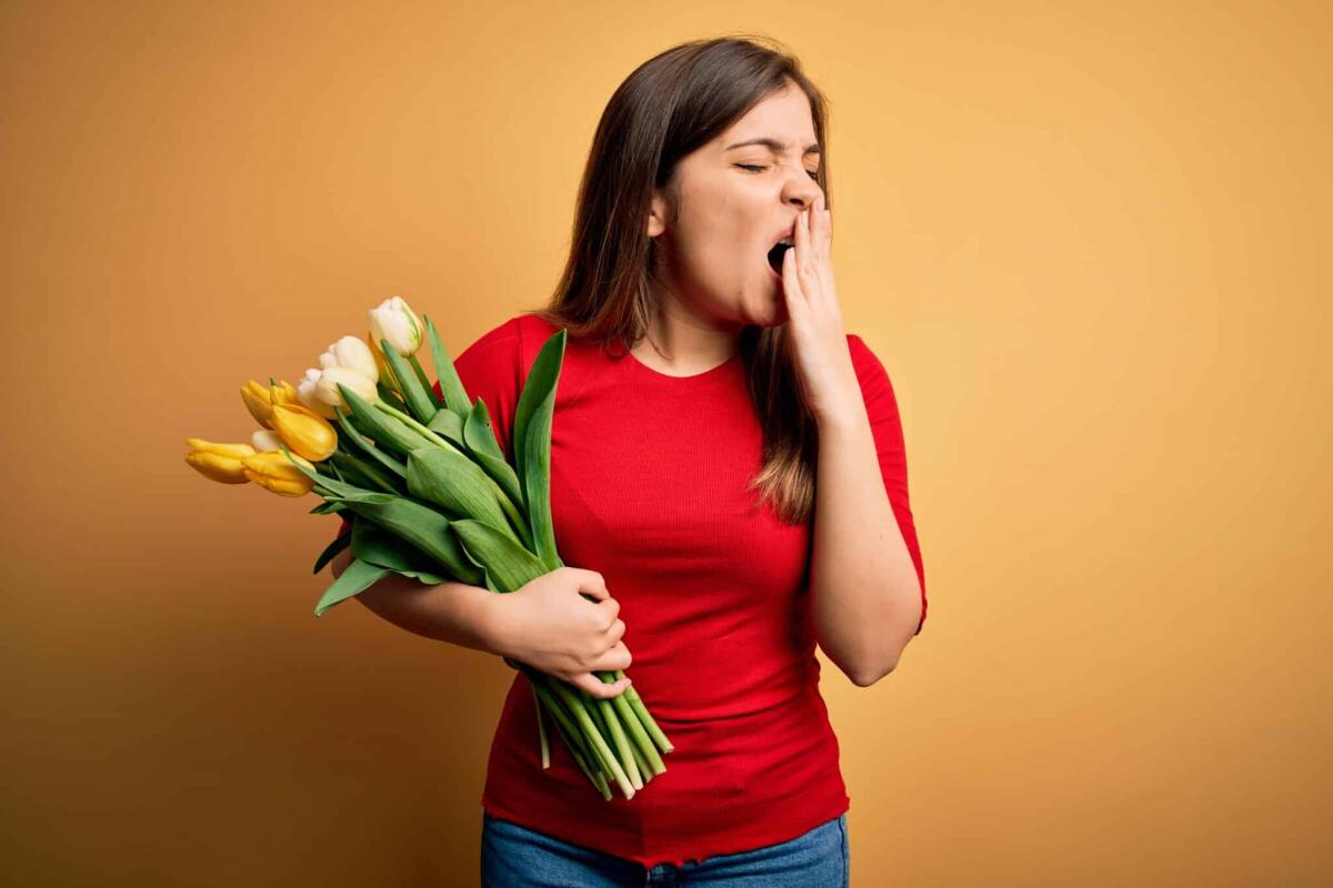 KO da bella stagione? Le regole per ritrovare l'energia in primavera - Young blonde woman holding romantic bouquet of tulips flowers over yellow background bored yawning tired covering mouth with hand. Restless and sleepiness.