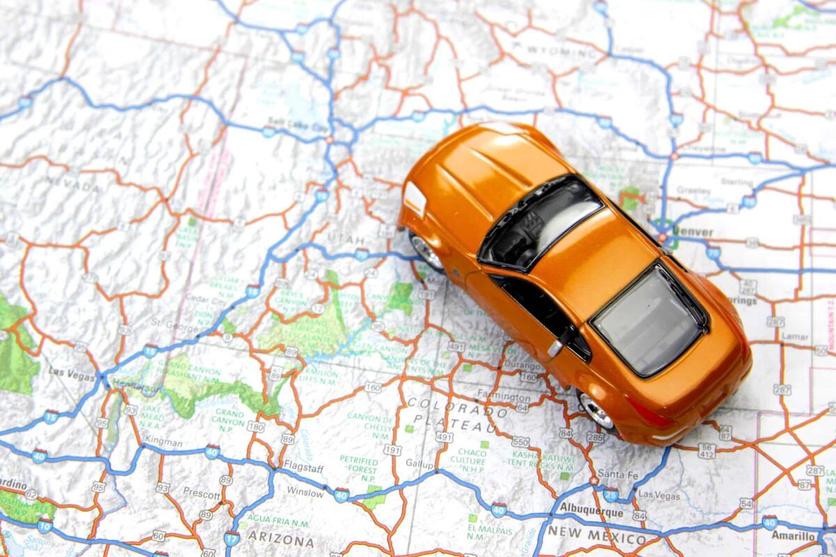 Le auto più comode e performanti per chi vuole fare un viaggio on the road - Orange sports car toy on map Road trip concept