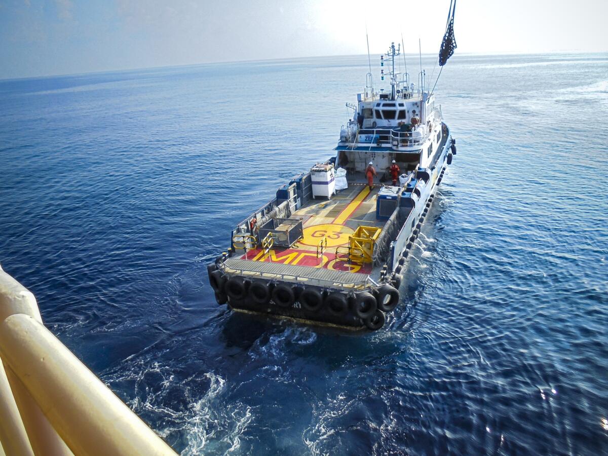 Dynamic Positioning: quando l’ormeggio non è possibile - The shipping box is loaded from an offshore oil rig to the supply vessel at sunset.