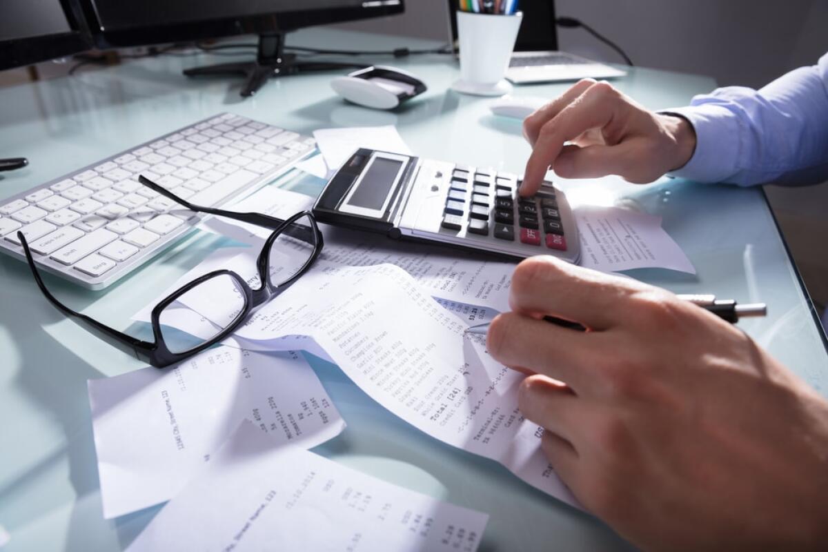 Tax Freedom Day: il giorno in cui smettiamo di lavorare per il fisco - Close-up Of A Businessperson's Hand Calculating Receipt At Workplace