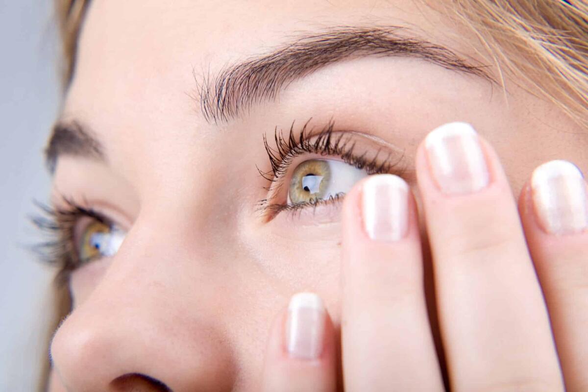 Occhio che trema: cause, sintomi, trattamento e cosa evitare - Opened green eyes and fingernails with french manicure close-up