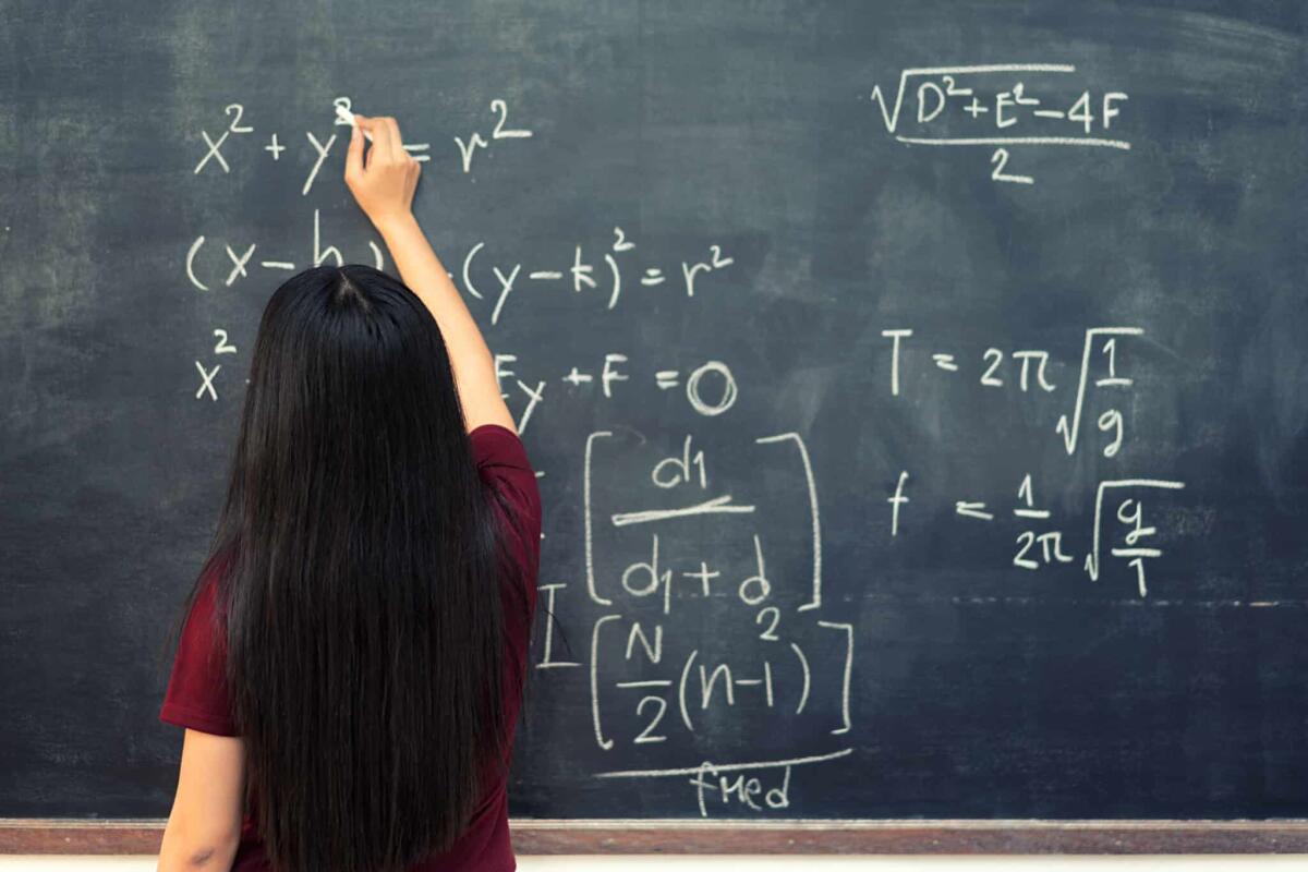Sophie Germain: la matematica sotto falso nome - Beautiful Asian student writing on blackboard with chalk in classroom.