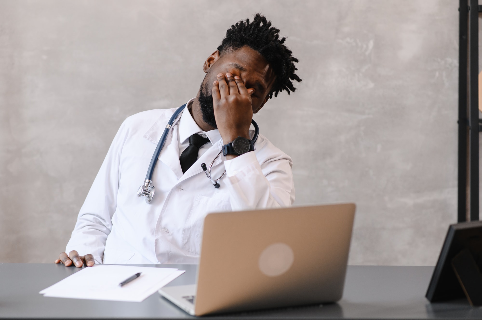 Funny bored at work african american doctor worker falling asleep at office desk, employee sleeping at workplace near laptop feel overworked concept. High quality photo