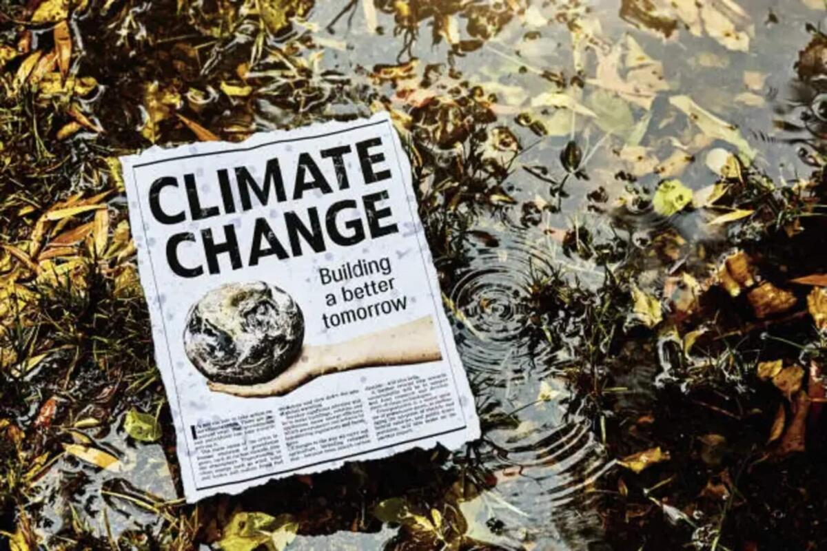 Perché i vecchi ritagli di giornale non dimostrano l'inesistenza del cambiamento climatico? - Cutting of simulated newspaper article about climate change outdoors in rainy weather in a swampy area. Text was written by the photographer, who also did the design and took the photo of the hand. Public domain satellite image from https://www.nasa.