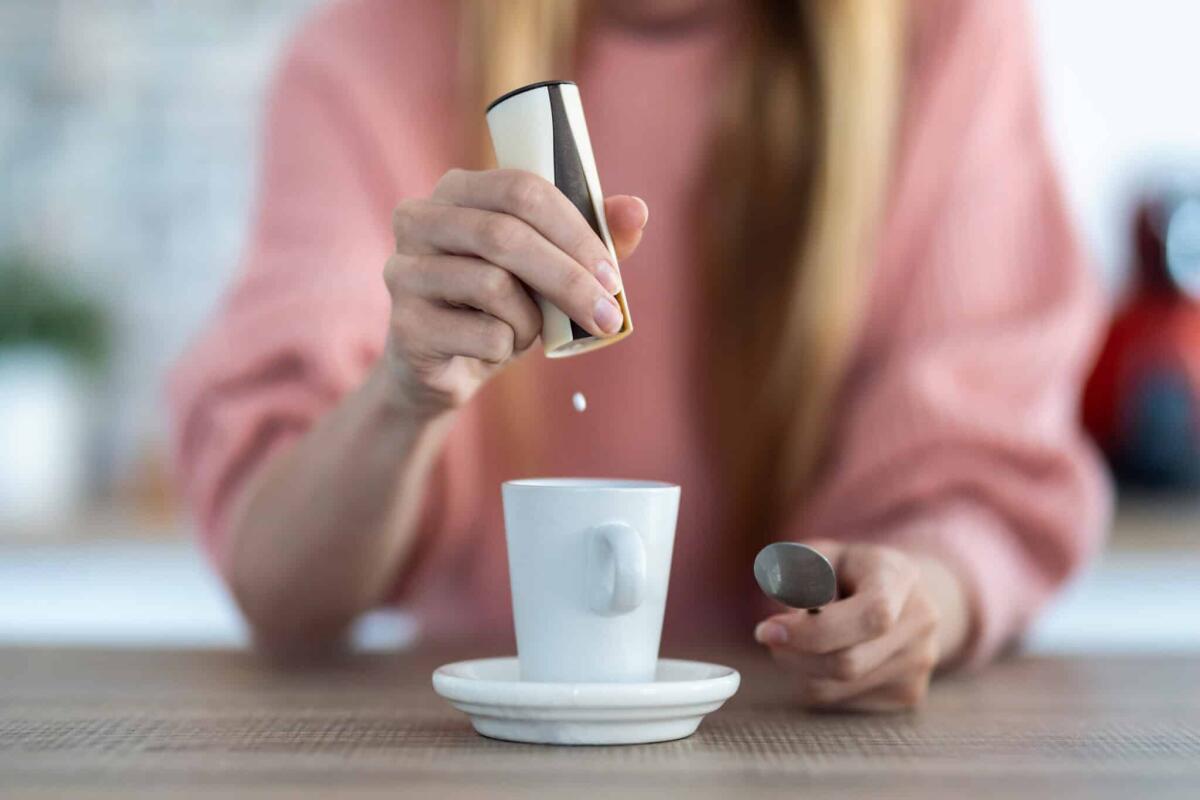 L'aspartame è davvero cancerogeno? Facciamo chiarezza - Close-up of woman hand throwing saccharin pills on coffee cup in the kitchen at home.