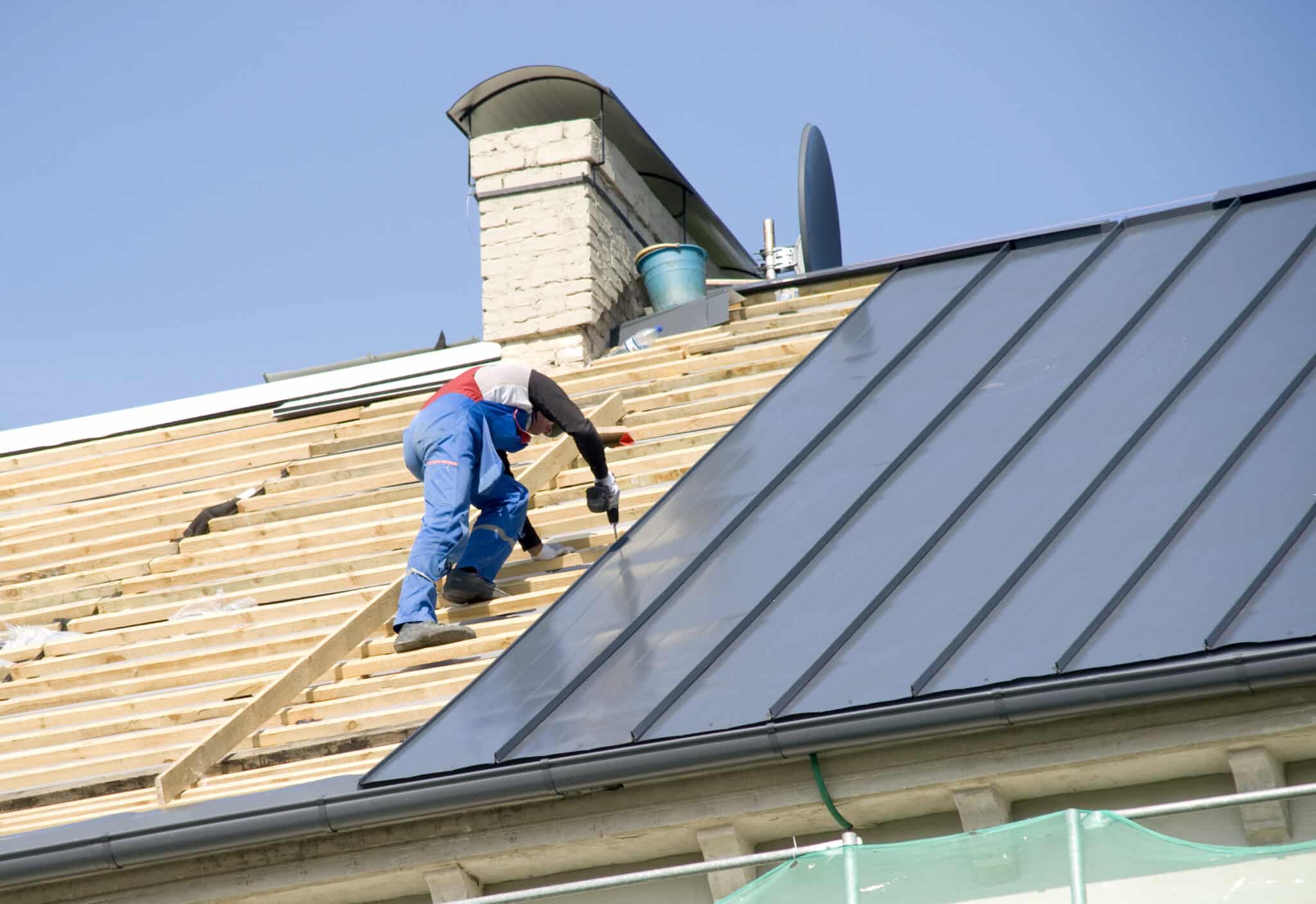The roofer behind work on repair a roof of the house