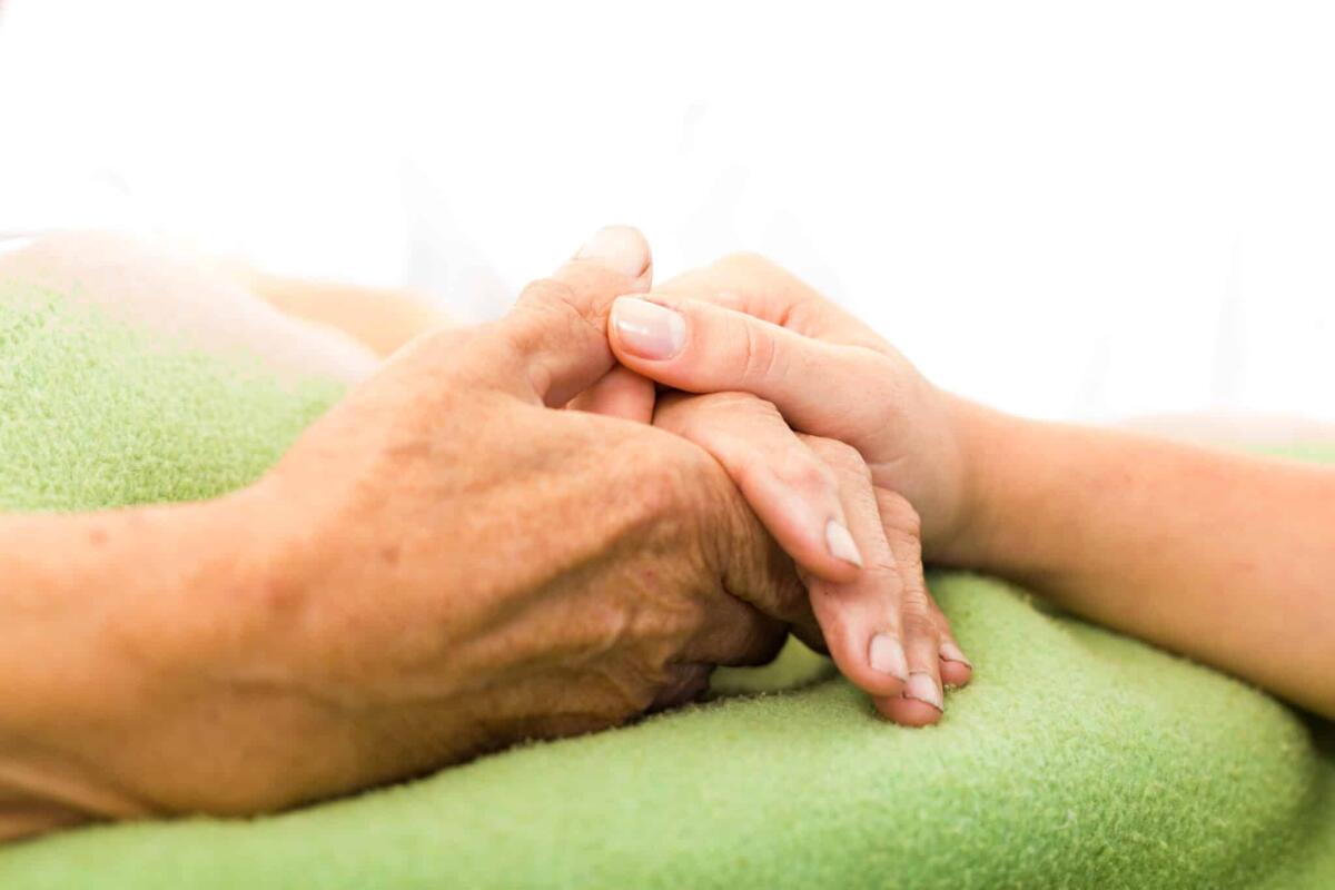 Il morbo di Parkinson dagli occhi può essere rilevato sette anni prima - Social services nurse holding elderly woman's hand with care.