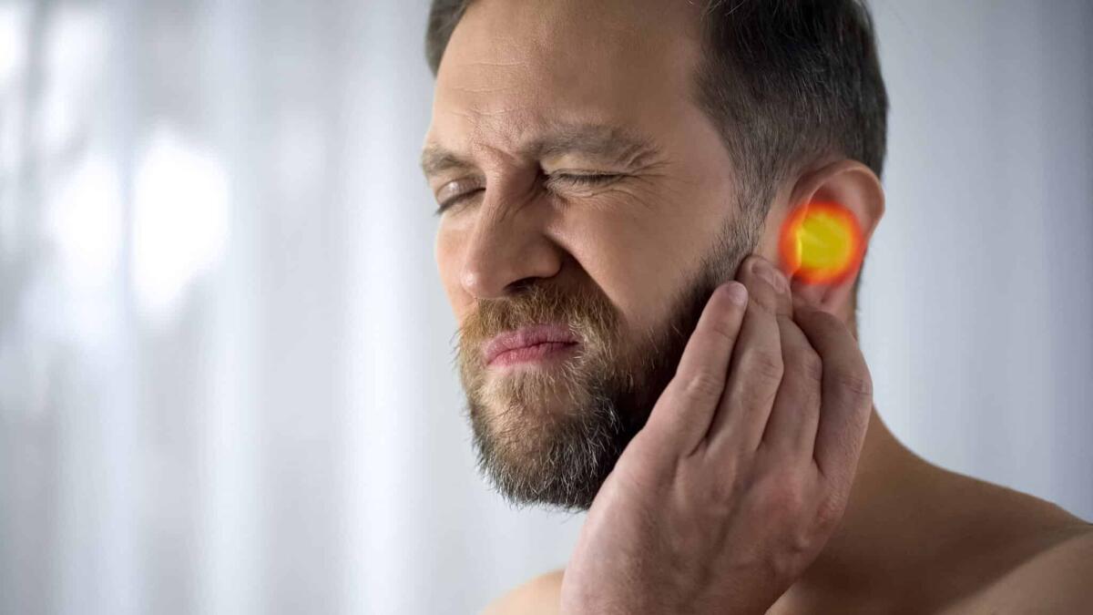 Consigli per prevenire l'otite durante l'estate - Man suffers from earache, otitis, hearing problems, spot indicates pain, closeup