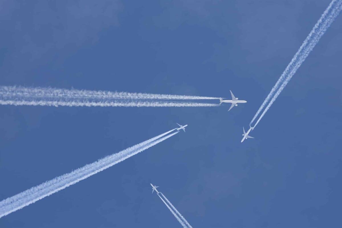 L'IA di Google potrebbe ridurre l'inquinamento delle scie di condensazione degli aerei - Passenger planes crossing with chemtrails in a blue sky