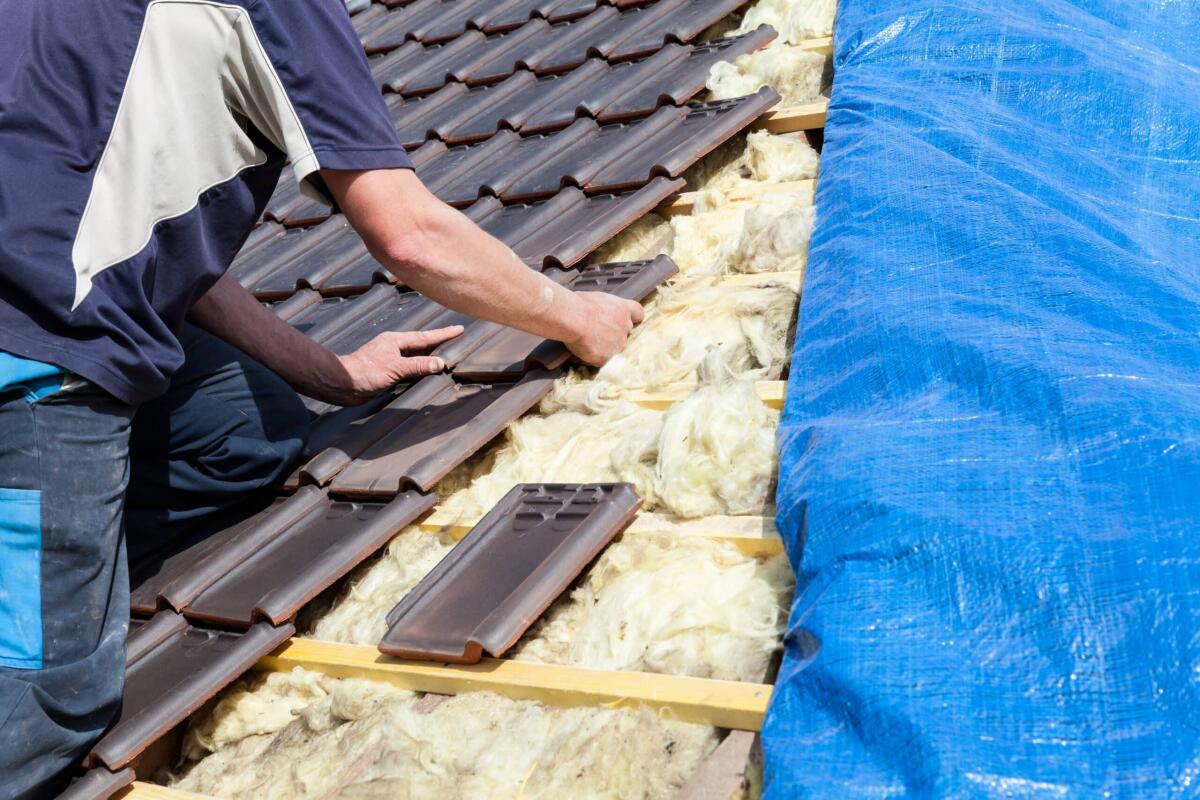 Rifacimento del tetto: quanto costa, interventi da realizzare ed errori da evitare - a roofer laying tile on the roof