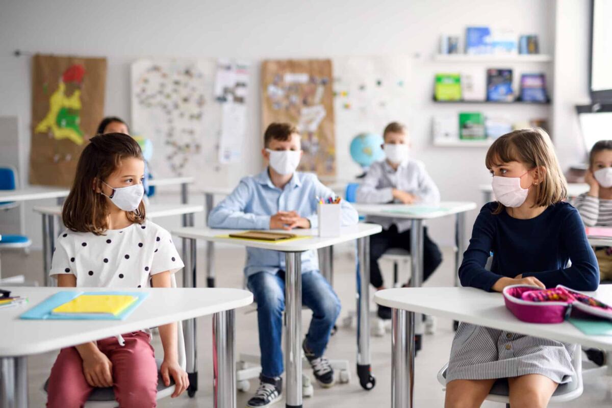 Covid e rientro a scuola: come comportarsi? - Small children with face mask back at school after covid-19 quarantine and lockdown.