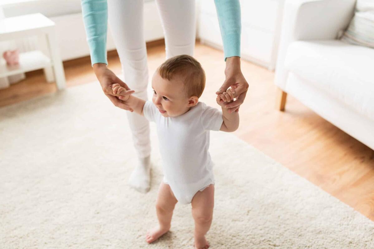 Bimbo di 15 mesi con SMA ritorna a camminare con una terapia genica - family, child, childhood and parenthood concept - happy little baby learning to walk with mother help at home