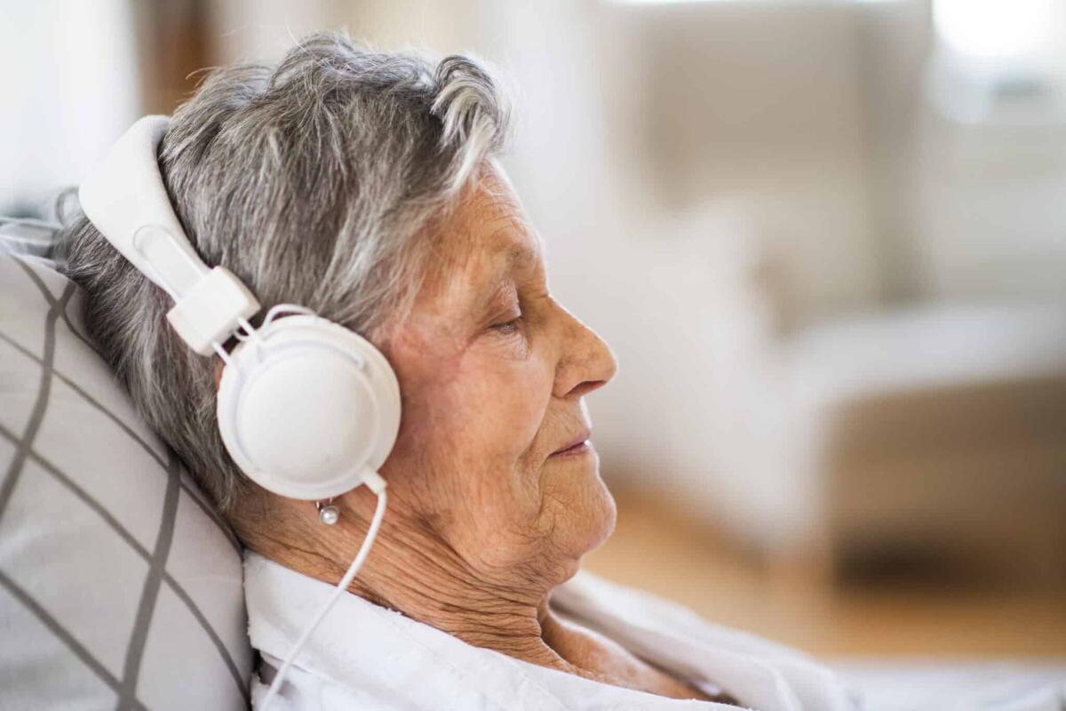 Una canzone dei Pink Floyd è stata registrata direttamente dal cervello - A close-up of sick senior woman with headphones lying in bed at home or in hospital, listening to music.