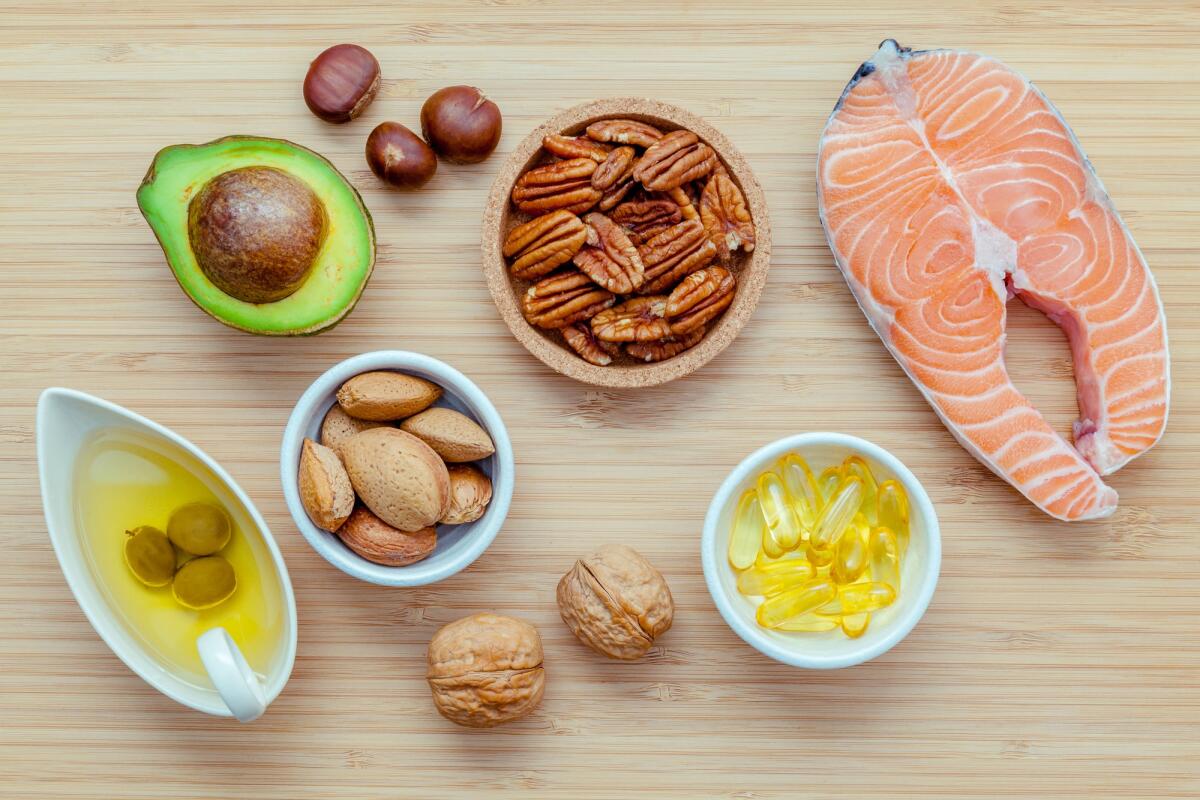 Quali sono i migliori prodotti e alimenti per dimagrire? - Selection food sources of omega 3 and unsaturated fats. Super food high omega 3 and unsaturated fats for healthy food. Almond ,pecan ,hazelnuts,walnuts ,olive oil ,fish oil ,salmon and avocado on wooden background .