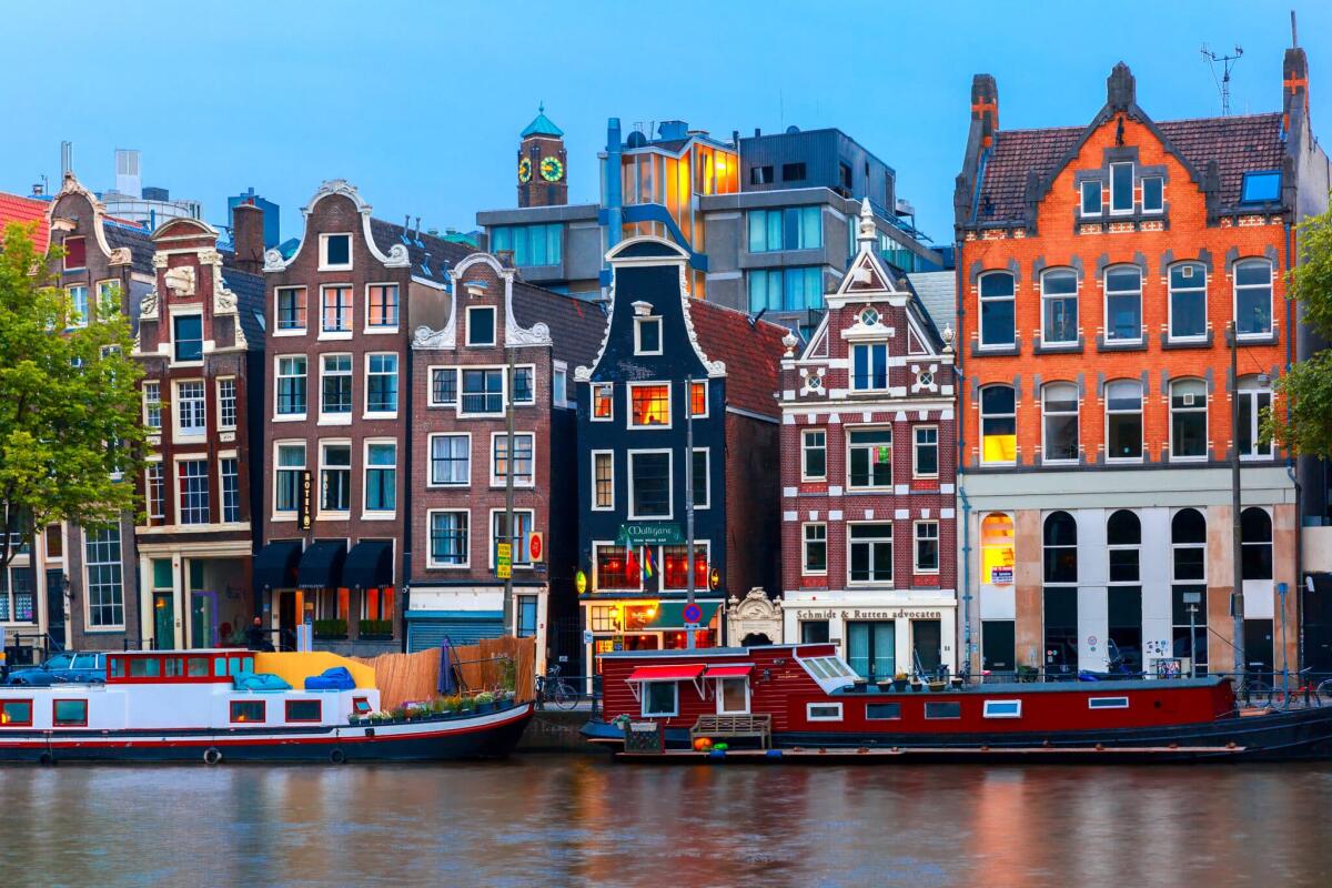 La tassa di soggiorno di Amsterdam aumenterà nel 2024 - Amsterdam, Netherlands - July 30, 2014: Night city view of Amsterdam canal, typical dutch houses and boats, Holland. Canal ring area placed on the UNESCO World Heritage List.