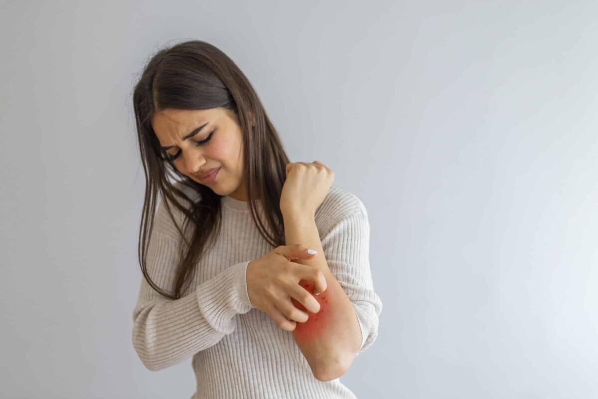 Orticaria acquagenica o "allergia all'acqua": cos'è e come si manifesta? - Woman Scratching an itch on white background . Sensitive Skin, Food allergy symptoms, Irritation. People scratch the itch with hand, Arm, itching, Concept with Healthcare And Medicine.