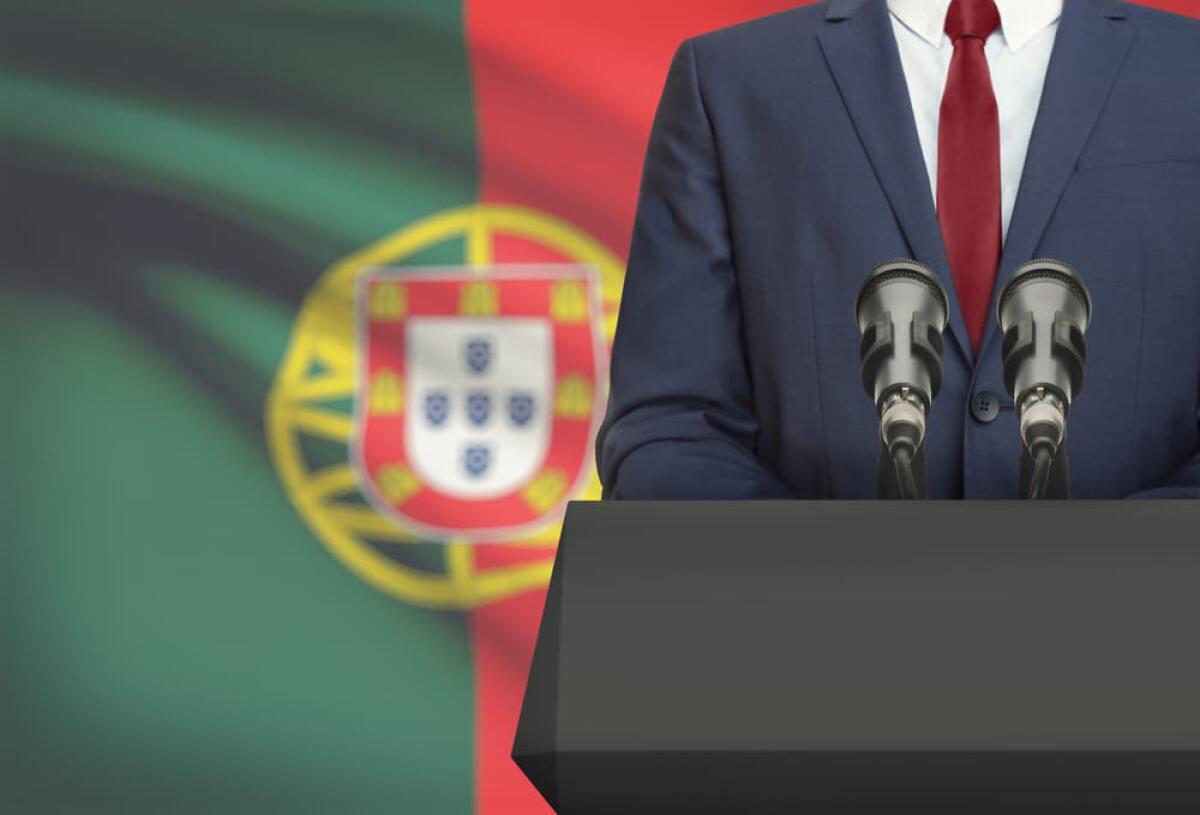Il Portogallo abbandona le agevolazioni fiscali per i pensionati stranieri nel 2024 - Businessman or politician making speech from behind the pulpit with national flag on background - Portugal