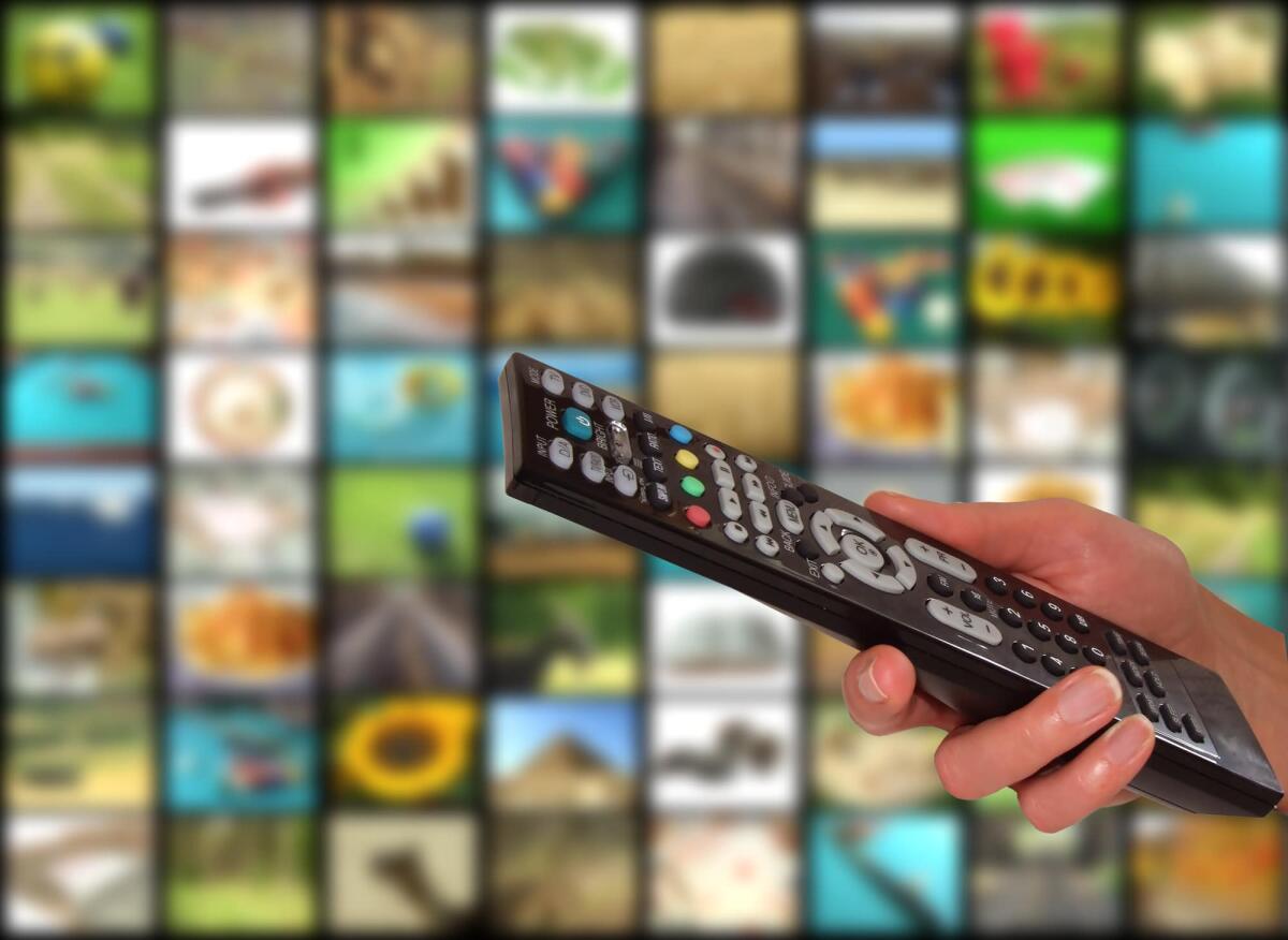 IPTV gratis: la lotta al pezzotto continua con multe salate e arresti - Remote in womens hand in front of multichannel background