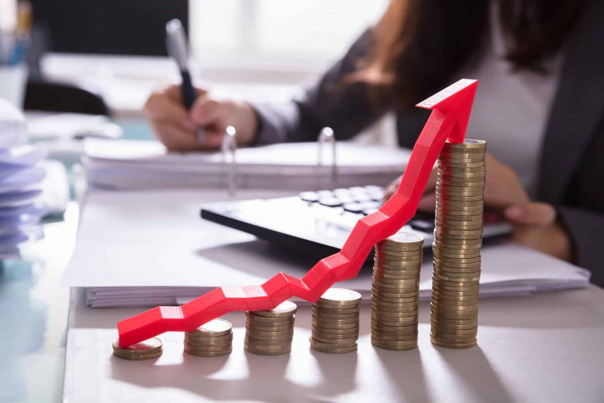 L’inflazione nell’Eurozona è in diminuzione - Increasing Golden Coins With Red Arrow Showing Upward Direction In Front Of Businessperson Calculating Bill
