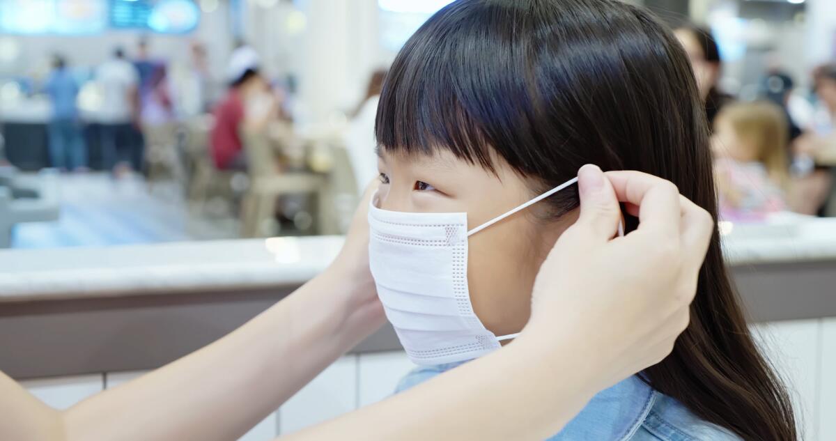 Polmonite in Cina: le raccomandazioni dell'OMS - Asian parents wear masks to their children because of transmissible infectious diseases indoor in the crowd